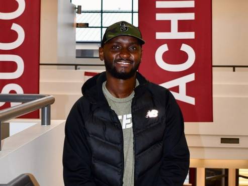 Dennis smiling at RTC campus with banner behind him