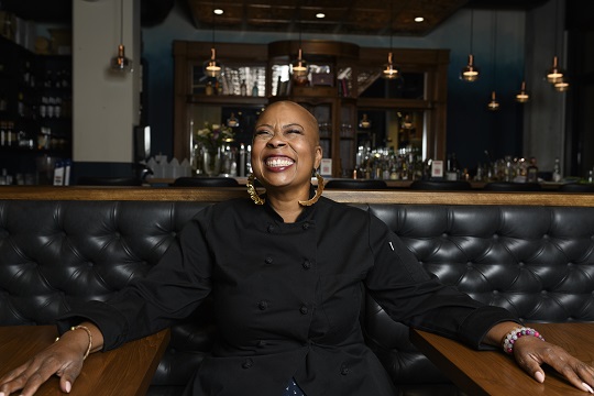 Chef Kristi Brown at a booth in a restaurant smiling