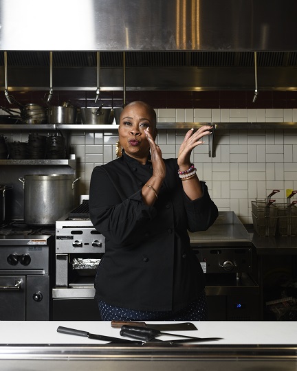 Chef Kristi Brown standing in a kitchen clapping