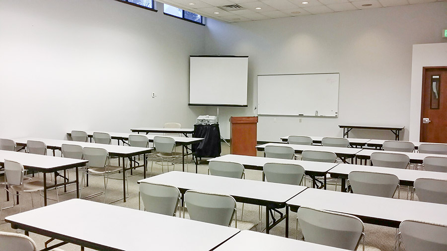 A large classroom seating 40 with a whiteboard and a screen in front.