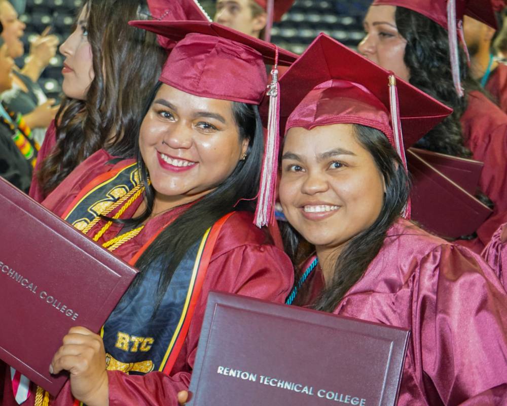 students smiling with their diploma