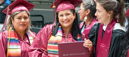 A group of students smiling as one holds a diploma