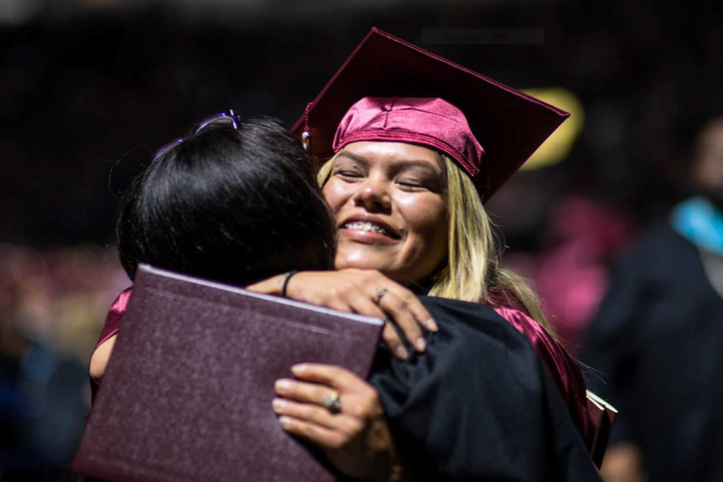 Two students hug each other at graduation.