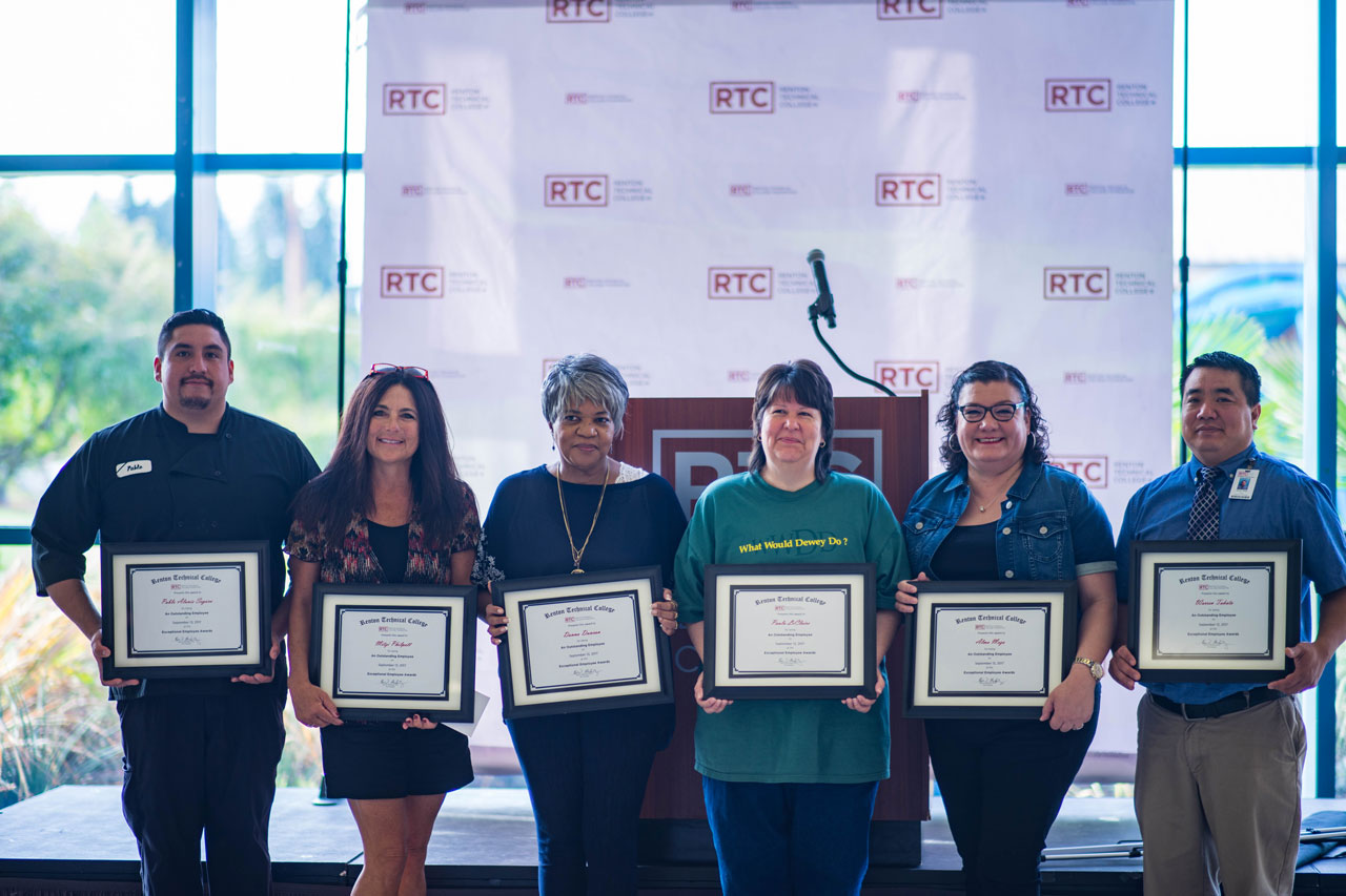 6 individuals posing with certificates in front of podium