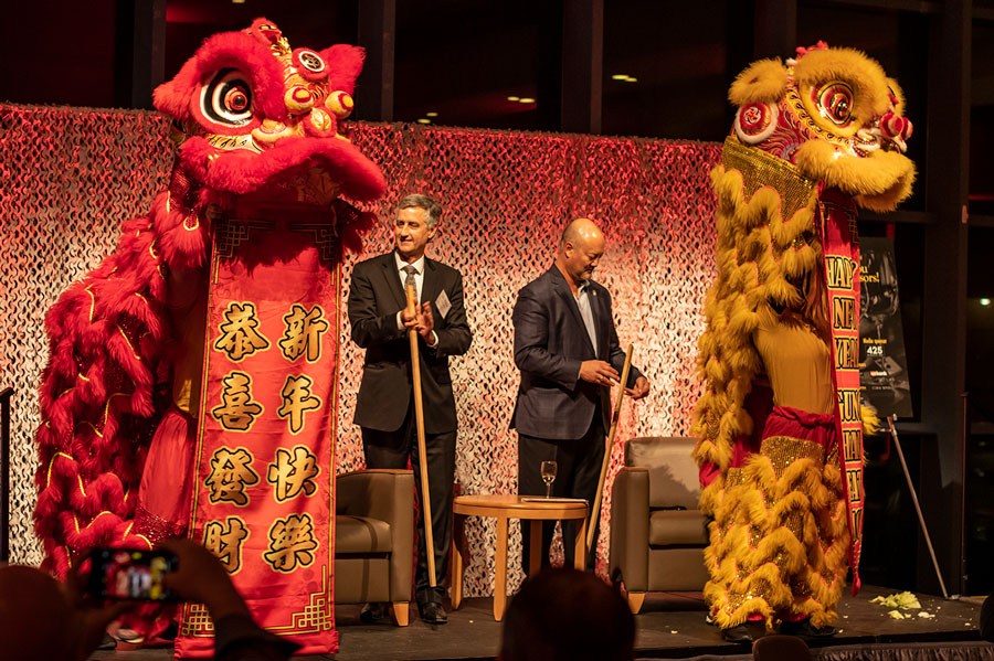 RTC President Kevin McCarthy and emcee Christopher Chan standing with two Lunar dragon suited performers on either side