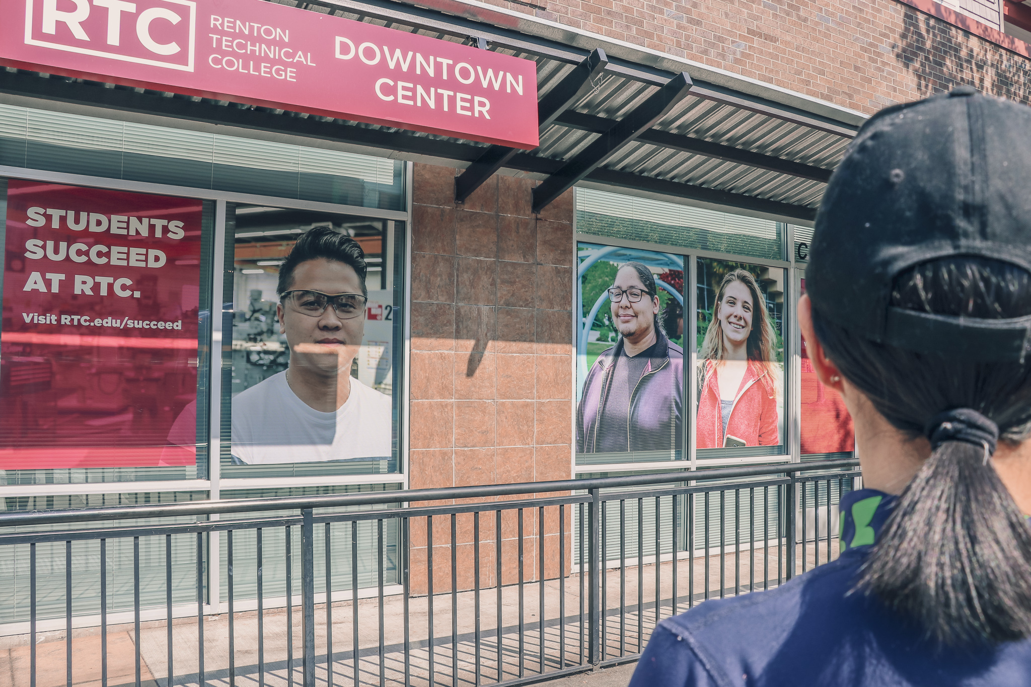 Passerby looks out to RTC Downtown Center Burnett Avenue facade with the newly developed displays featuring RTC student and message "Students Succeed at RTC."