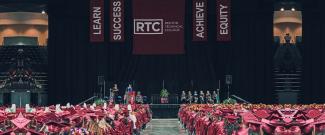 Commencement event showing students in the audience and speakers on stage with RTC banners above them
