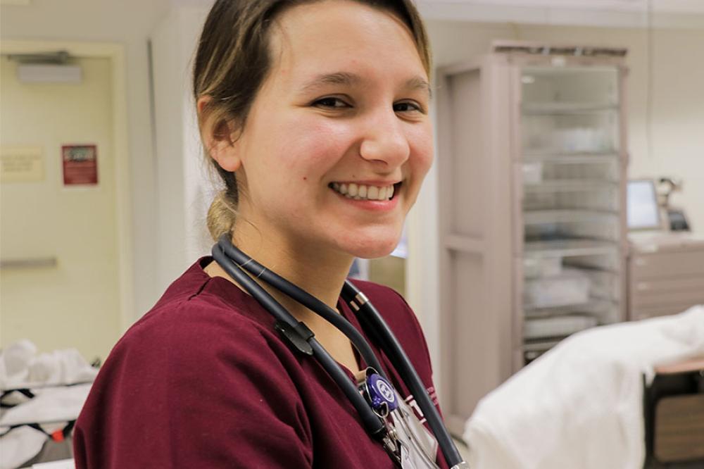 student in maroon scrubs smiling