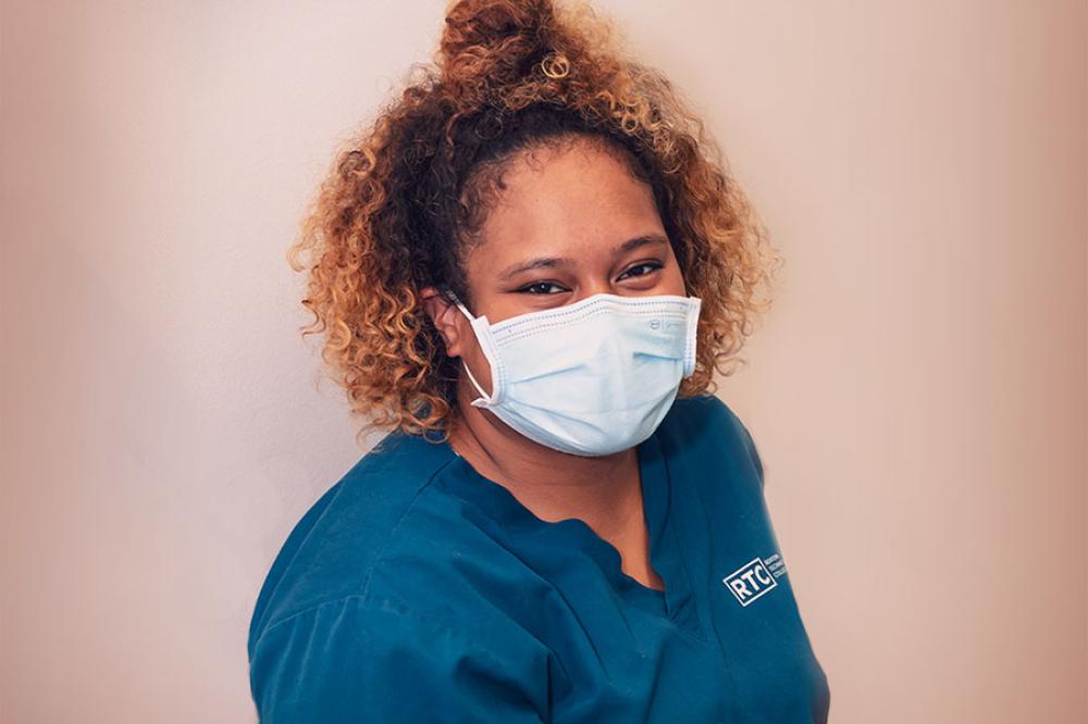 Student in blue scrubs and face mask